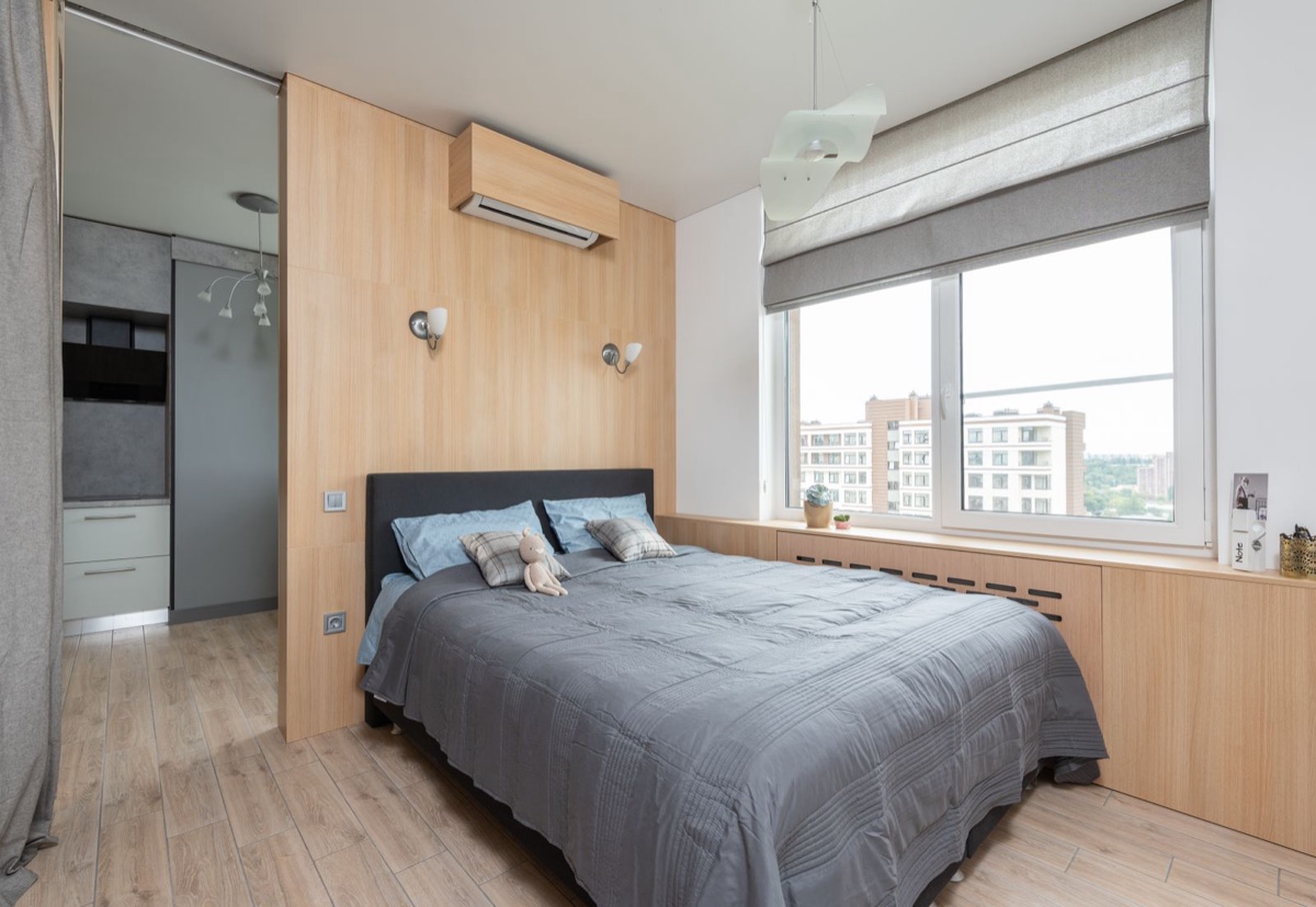 Bright bedroom with a wall-mounted mini split indoor unit set into a wood panel, one of the three heads the best DIY 3 zone mini split runs from a single outdoor condenser